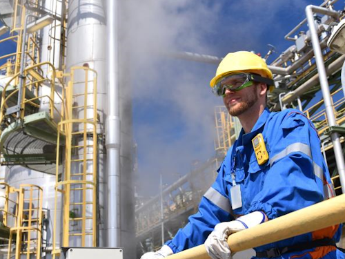 Chemical Engineer - a scientist in a hard hat and safety glasses looking out over a waste treatment plant