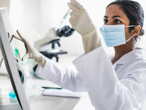 Epidemiologist - a scientist in a lab coat and gloves holding up a test tube