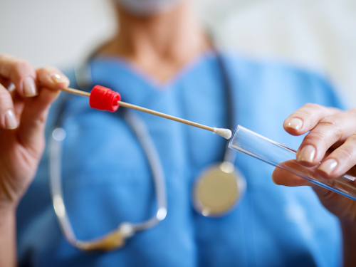 Forensic Nurse - a nurse in blue scrubs putting a sample into a vial