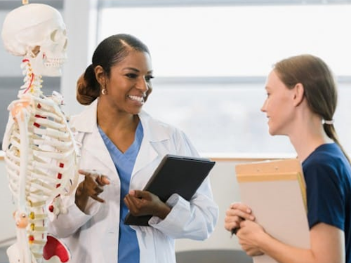 Health Educator - A scientist in a lab coat talking to a woman