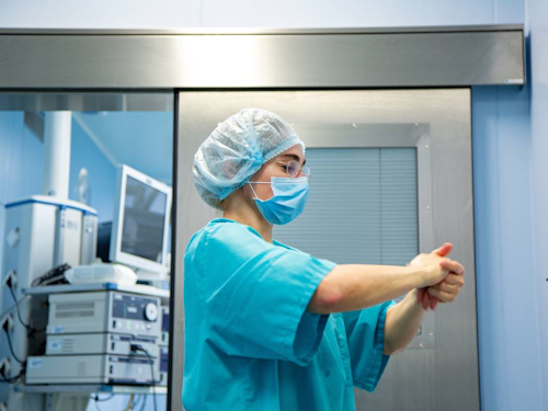 Infection Control Nurse - a nurse in blue scrubs and a hair cap washing their hands