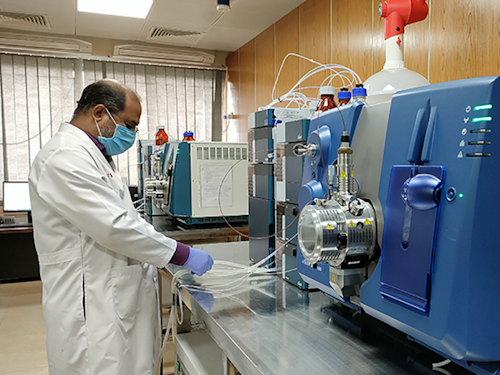 Zoonotic Disease Specialist - a scientist in a food safety lab standing in front of a machine that measures isotopes